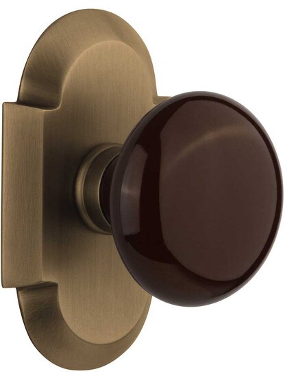 Arched Rosette Door Set with Brown Porcelain Knobs in Antique Brass.
